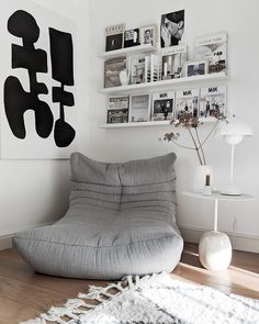 a living room filled with furniture and pictures on the wall next to a white rug