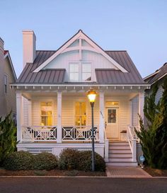 a white house with porches and stairs leading up to the front door at dusk