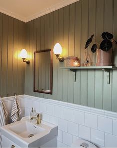 a white sink sitting under a bathroom mirror next to a wall mounted faucet