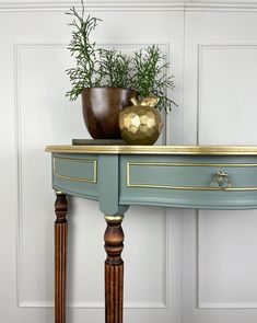 a table with two vases on top of it and a plant in the middle