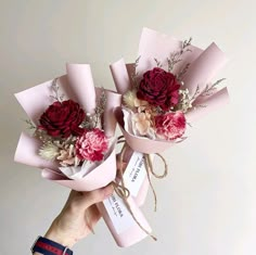 two bouquets of flowers are wrapped in pink paper