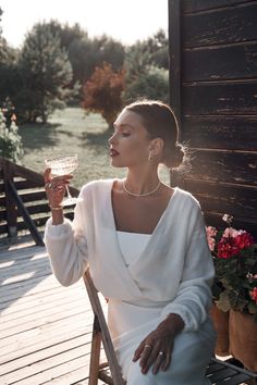 a woman sitting on a chair holding a wine glass in one hand and looking off into the distance