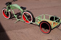 a green bike with red rims parked on the street next to a bicycle trailer