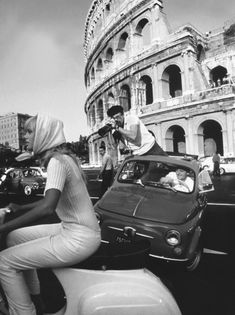 black and white photograph of people on scooters in front of the colossion