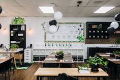 the interior of a restaurant with tables, chairs and plants on the wall above them