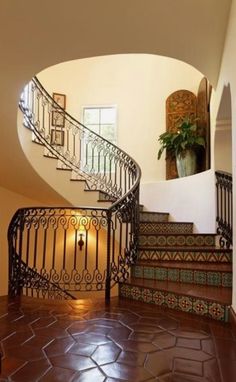 a spiral staircase in a home with tiled flooring and handrails leading up to the second floor