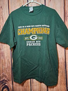 This listing is for a pre-owned vintage Green Bay Packers 2003 NFC North Division Champions T-Shirt, Size Large.  Delta Pro Weight Shirt, 100% Cotton.  It's in great, pre-owned condition and appears minimally worn.  No rips or stains.  It measures 21" from armpit to armpit, 16.25" from armpit to waist, 27.5" from collar to waist, and 4.75" from armpit to end of sleeve.  See pictures for best idea of condition. Items come from a smoke free home.  Sold as is, returns are not accepted. Please remem Green Sports Season T-shirt For Fan Gear, Green T-shirt For Sports Season Fan Gear, Green Fan Merchandise T-shirt For Sports Season, Green T-shirt With Logo For Sports Season, Vintage T-shirt For Sports Season Fan Gear, Vintage Fan Gear T-shirt For Sports Season, Green Bay Packers, Green Bay, Favorite Outfit