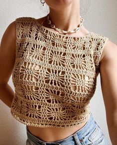 a woman wearing a crochet top with her hands in her pockets and smiling