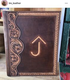 a brown leather book with an arrow on the cover and decorative border around the corner