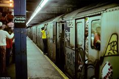 people are standing on the side of a subway train as it's pulled up to the platform