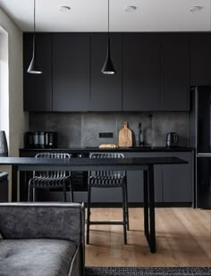 a kitchen with black cabinets and wooden floors