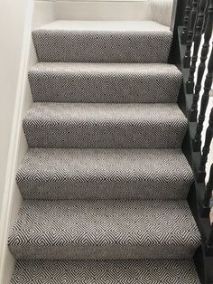 some stairs with black and white carpet on the bottom, and another stair case in the background