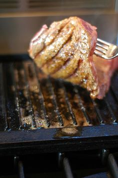 a piece of meat is being grilled on the grill with a fork in it