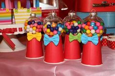 three red vases filled with candy on top of a table