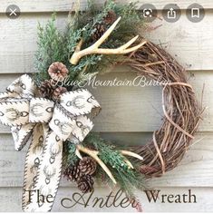 a wreath with antlers and pine cones hanging on the side of a building that reads, the antler's wreath