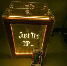 a remote control sitting in front of a lighted box with just the tip written on it