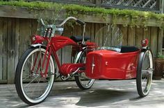 an old fashioned red motorcycle with sidecar parked on a wooden deck in front of a fence