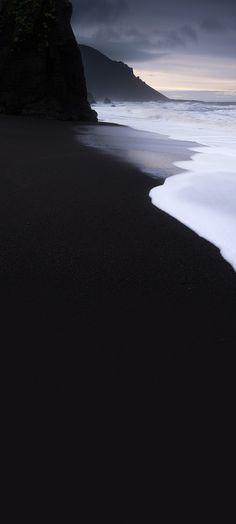 black sand beach with waves coming in to shore