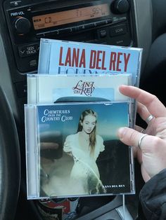 a person holding up two cd's in their hand while sitting in a car