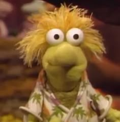 the muppet is dressed in pajamas and looking at something with big eyes on his face