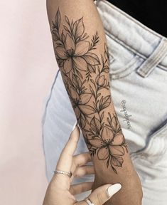 a woman's arm with a flower tattoo on the left forearm and right arm