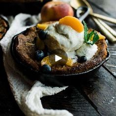 a bowl filled with fruit and ice cream on top of a wooden table