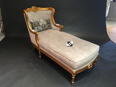 an antique chaise lounge is displayed in front of a black backdrop with white and gold accents