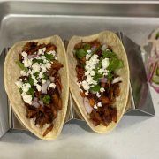 three tacos sitting on top of a metal tray