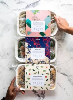 three plastic containers filled with food on top of a marble countertop next to each other