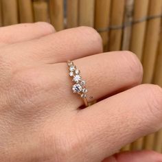 a woman's hand with a diamond ring on top of her finger and bamboo sticks in the background