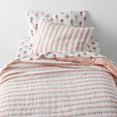 a bed with pink and white striped bedspread, pillows and pillowcases