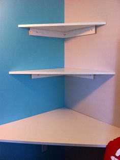 a corner shelf in the corner of a room with blue walls and white shelving