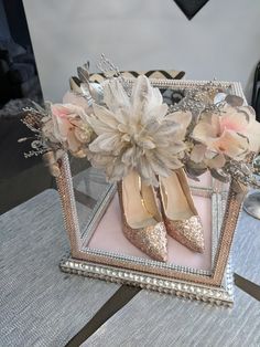 a pair of high heeled shoes sitting on top of a table next to flowers