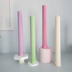 three different colored candles sitting next to each other on top of a table in front of a mirror