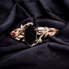 an elegant black stone ring on top of a purple silk cloth with gold chains and leaves