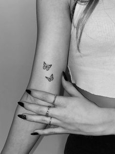 two women with tattoos on their arms and one has a butterfly tattoo on her arm