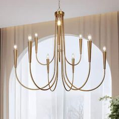 a chandelier hanging from the ceiling in front of a large window with curtains