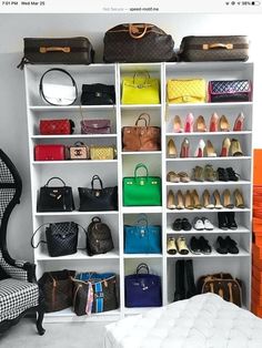 a closet filled with lots of purses and handbags next to a white chair