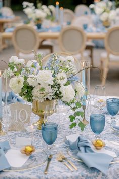 the table is set with blue and white linens, silverware, and flowers