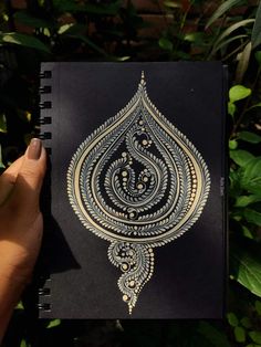 a hand holding up a notebook with an intricate design on it