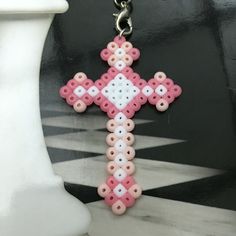 a pink and white cross is hanging from a chain on a black and white checkered floor