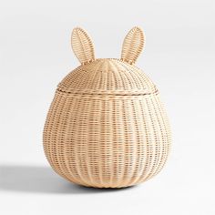 a wicker basket with ears on the top and bottom, sitting in front of a white background