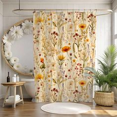 a bathroom with a flower shower curtain next to a round mirror and potted plant