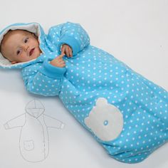 a baby laying on its side wearing a blue sleeping bag