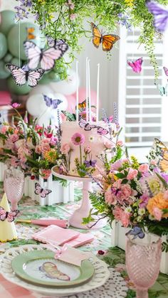 a table topped with lots of pink flowers and butterflies on top of it's tables