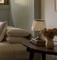 a bed with two pillows on top of it next to a lamp