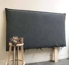 a large gray headboard sitting on top of a wooden stool next to a wall