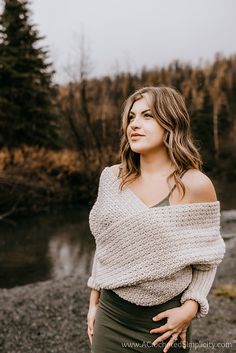 a woman standing in front of a river with her hands on her hips and looking off to the side