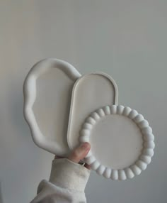 a person holding two white plates in their hands, one is shaped like an elephant