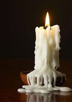 a candle that is sitting on top of a wooden bowl with liquid flowing around it